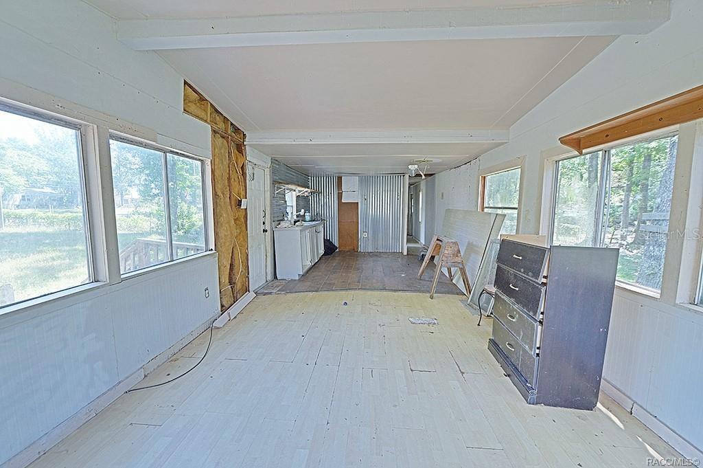 An unfinished sunroom features exposed wall insulation, a corrugated metal wall, and light-colored flooring — 5332 E SOUTH CROSSING COURT, INVERNESS, FL