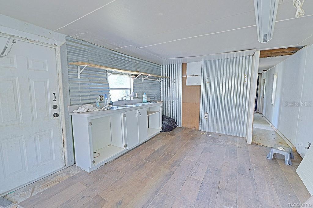 A utility room features corrugated metal walls, a sink cabinet, and wood-look tile flooring — 5332 E SOUTH CROSSING COURT, INVERNESS, FL