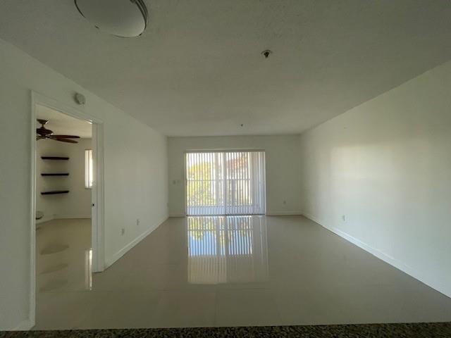 An empty living room with white walls, tile flooring, and a sliding glass door — 470 S Park Road # 302, Hollywood FL 33021, HOLLYWOOD, FL