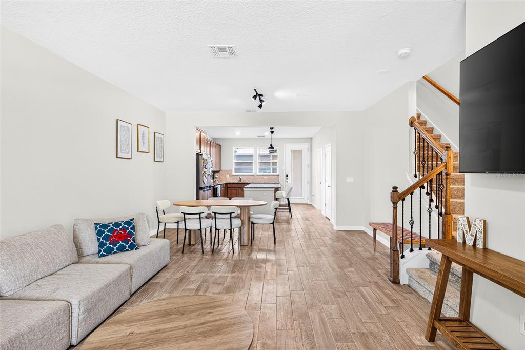 An open-concept living and dining area features wood-look tile flooring and a staircase — 5133 SAPLING SPROUT DRIVE, ORLANDO, FL