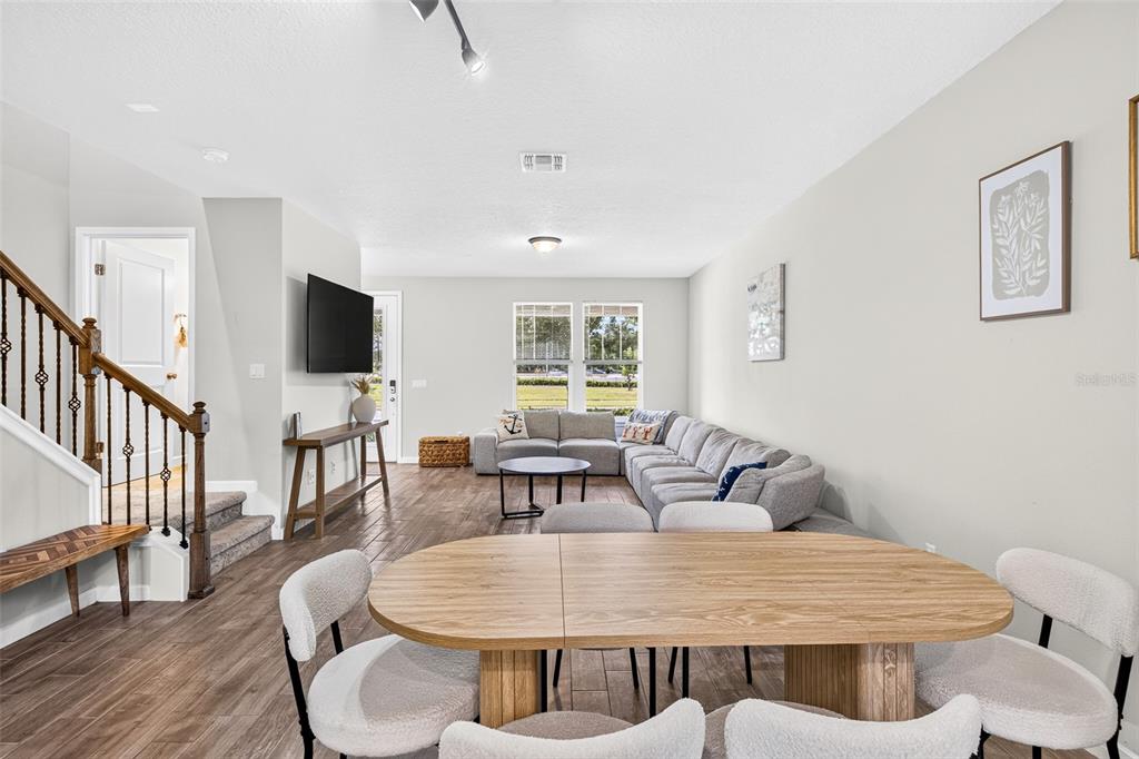 A living room and dining area feature wood-look flooring, a sectional sofa, and a staircase — 5133 SAPLING SPROUT DRIVE, ORLANDO, FL