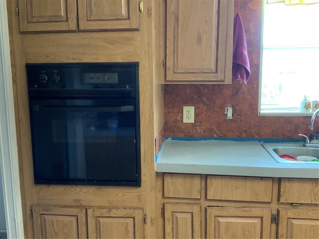 A kitchen features wood cabinets, a built-in black oven, and a sink with countertops — 1639 BASS AVENUE, SEVILLE, FL