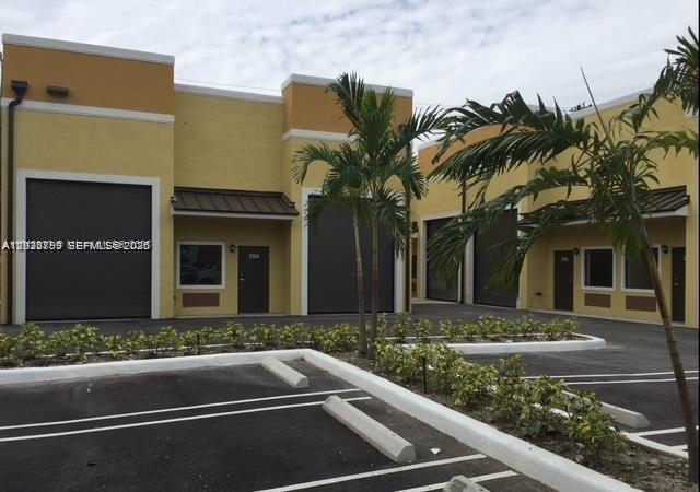 A row of yellow commercial warehouse units with roll-up doors and palm trees in front — 2188 NW 26th Ave, Miami FL 33142, MIAMI, FL