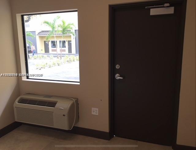 An interior view showing a window, a wall-mounted air conditioning unit, and a dark door — 2188 NW 26th Ave, Miami FL 33142, MIAMI, FL