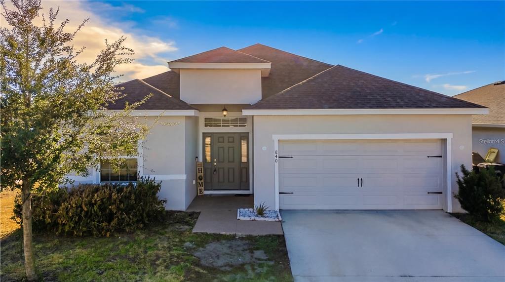 A single-story house with a beige stucco exterior, a two-car garage, and a front entryway — 840 SYDNEY STREET, DAVENPORT, FL