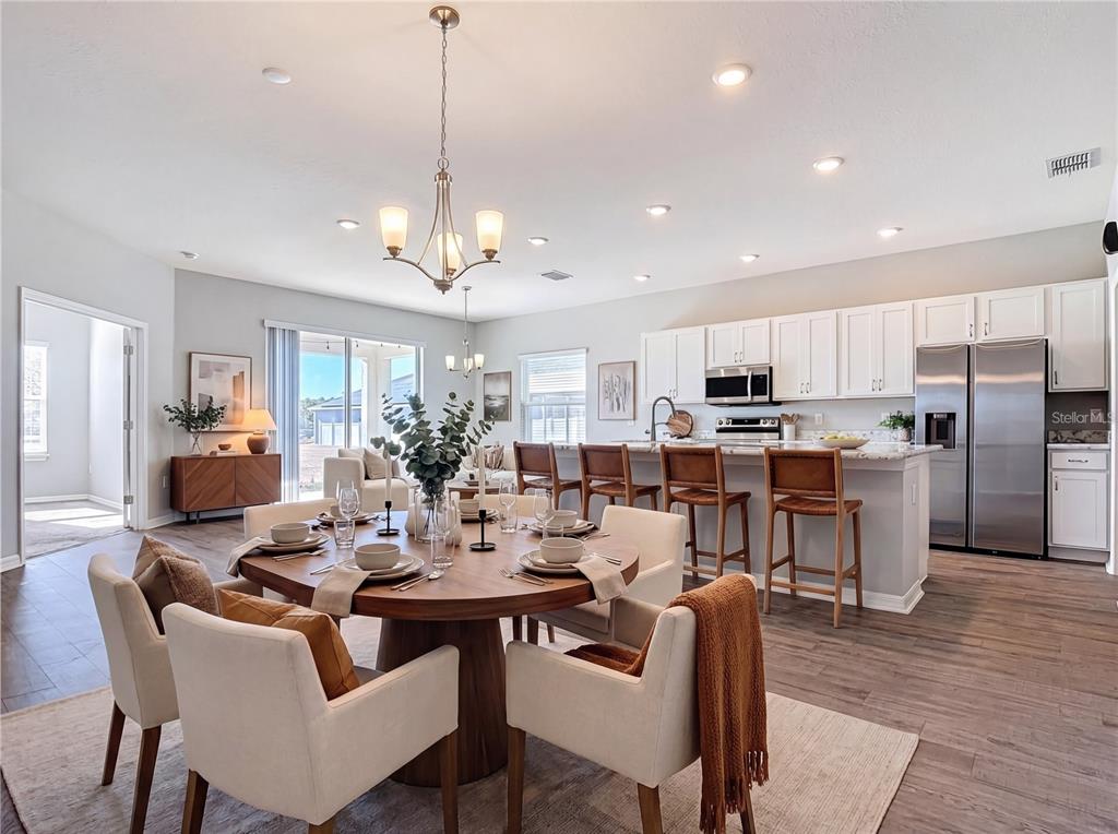 An open-concept kitchen and dining area features white cabinets, stainless appliances, and a round table — 840 SYDNEY STREET, DAVENPORT, FL