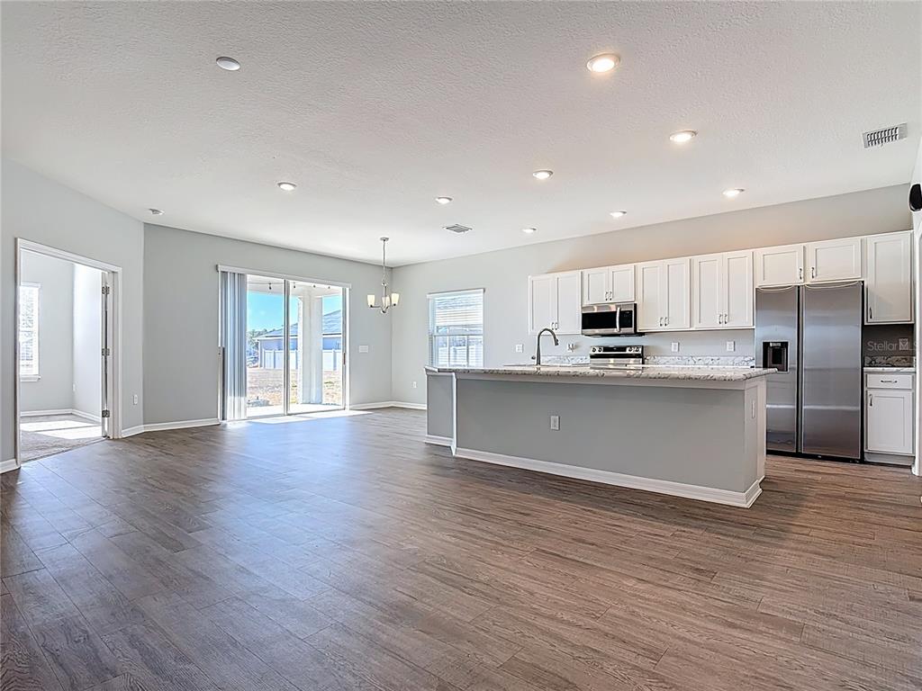 A kitchen with white cabinets and a center island opens into a spacious living area — 840 SYDNEY STREET, DAVENPORT, FL