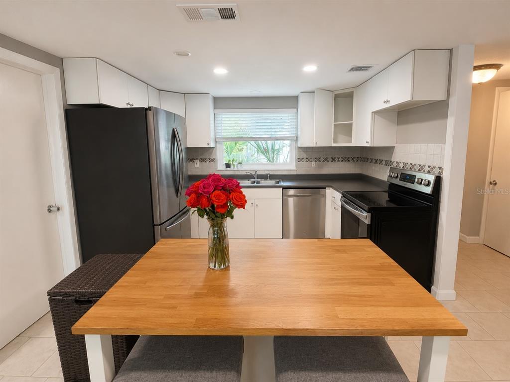 A kitchen features white cabinets, stainless steel appliances, a black stove, and a wooden island — 10124 HOLLY DRIVE, PORT RICHEY, FL