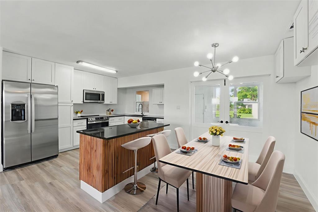 A modern kitchen and dining area features white cabinetry, a wood-slatted island, and stainless appliances — 8812 OAKWOOD DRIVE, LAKE WALES, FL
