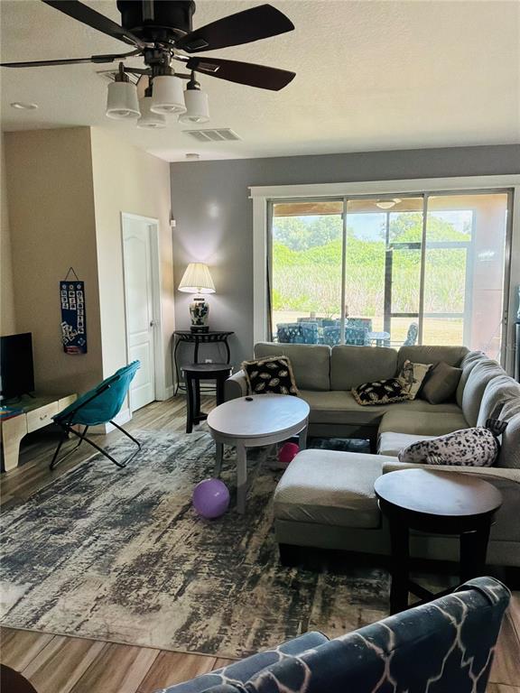 A living room features a sectional sofa, a ceiling fan, and a large sliding glass door — 308 CORBETT BLUFF DRIVE, RUSKIN, FL