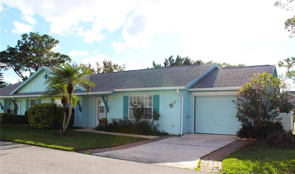 A light blue single-story house with a garage, a driveway, and a small palm tree — 26 FORE DRIVE, NEW SMYRNA BEACH, FL