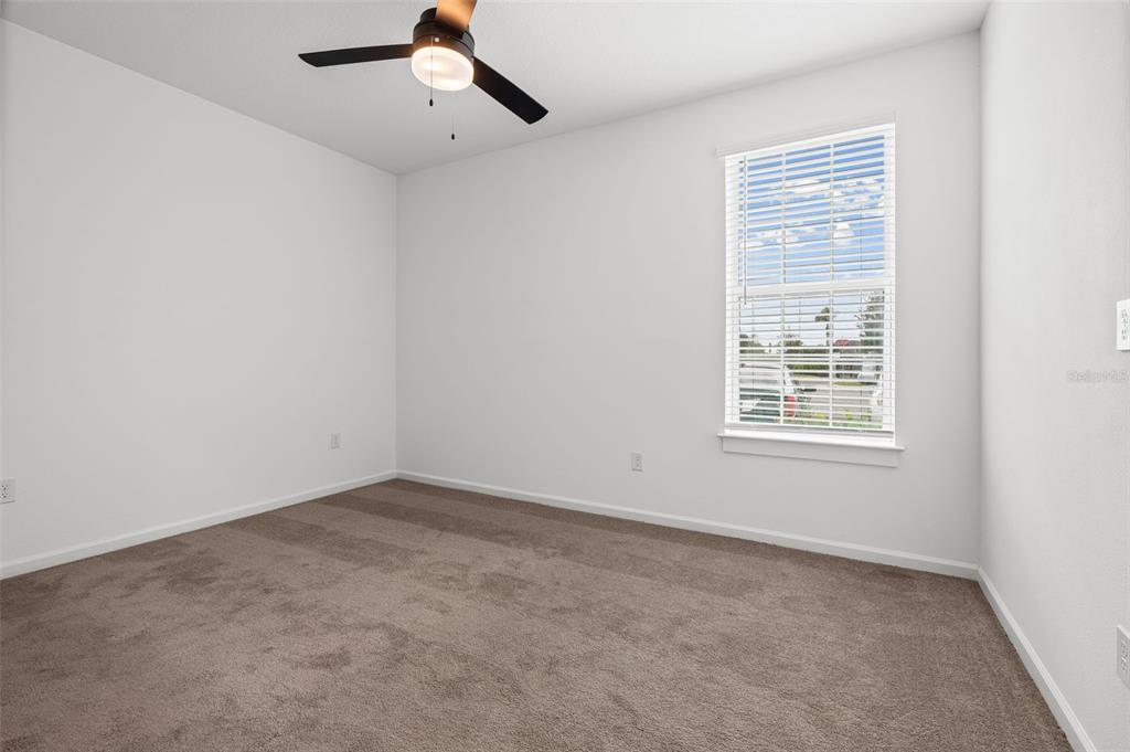 An empty bedroom features white walls, tan carpeting, a ceiling fan, and a single window — 1700 RANCH ROAD UNIT B2-6107, NOKOMIS, FL