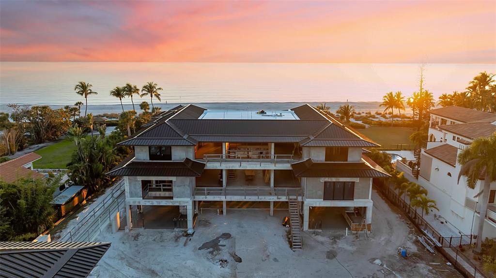 An aerial view of a multi-story house under construction facing the ocean at sunset — 5965 GULF OF MEXICO DRIVE, LONGBOAT KEY, FL