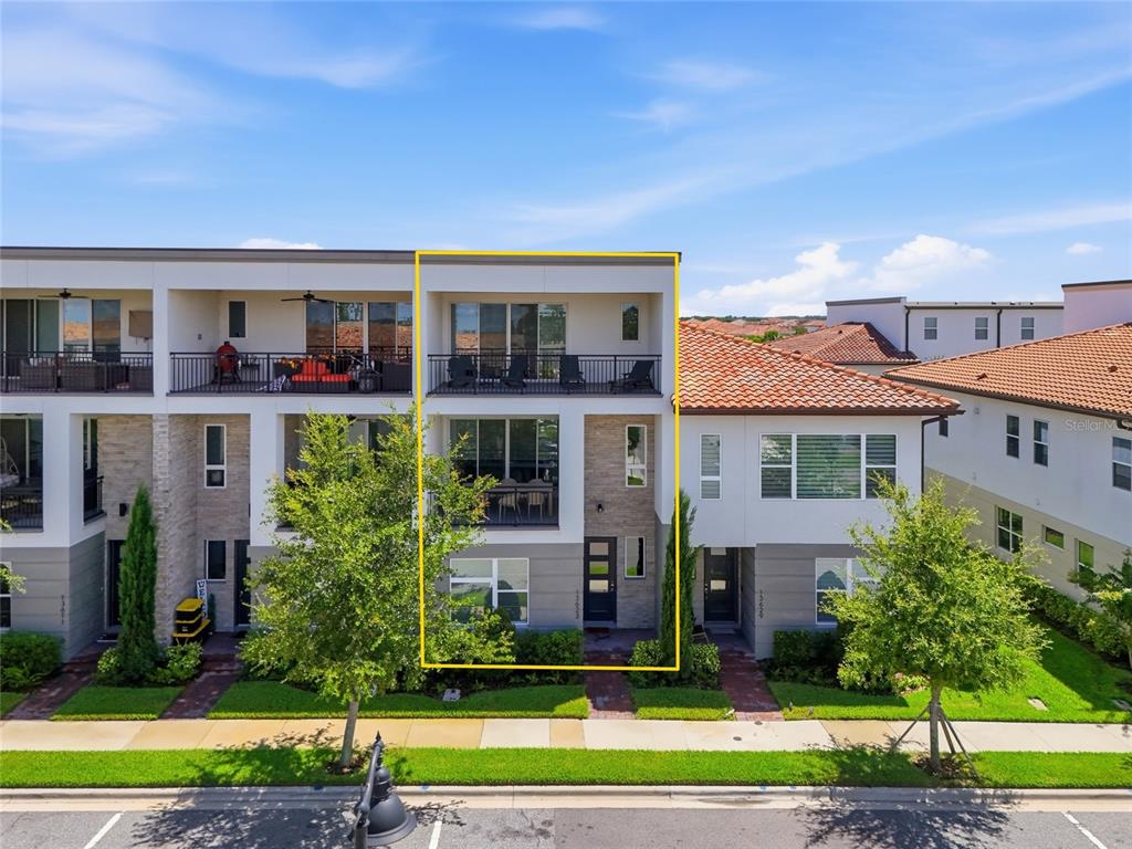 A three-story townhouse exterior with a yellow outline highlighting the middle unit — 13623 LARKTON LANE, ORLANDO, FL