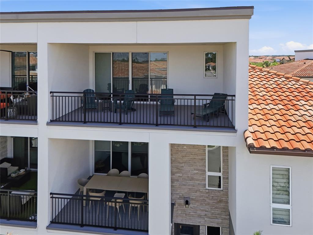A two-story building exterior features stacked balconies with metal railings and a stone-accented wall — 13623 LARKTON LANE, ORLANDO, FL