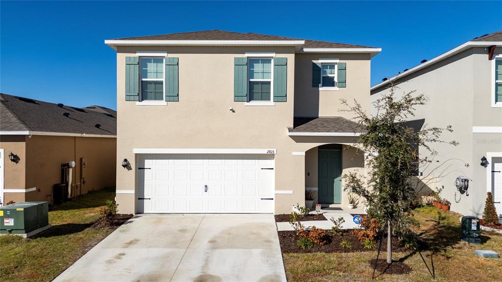 A two-story suburban house with a beige stucco exterior, a two-car garage, and teal shutters — 2815 MOULIN ROAD, DAVENPORT, FL