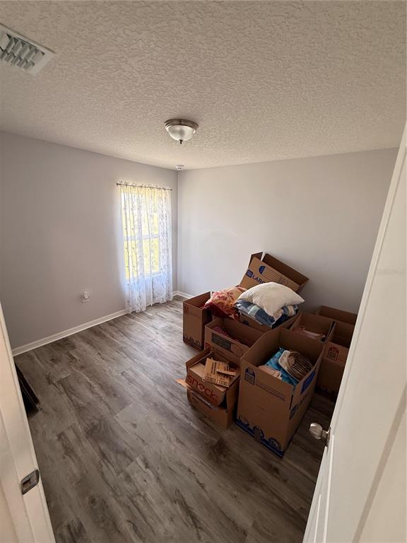 A bedroom with light gray walls, wood-look flooring, and several cardboard moving boxes — 2185 ROCK DRIVE, POINCIANA, FL