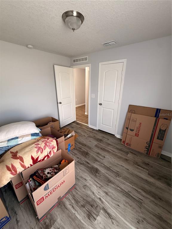 A room with light gray walls, wood-look flooring, two white doors, and several cardboard boxes — 2185 ROCK DRIVE, POINCIANA, FL