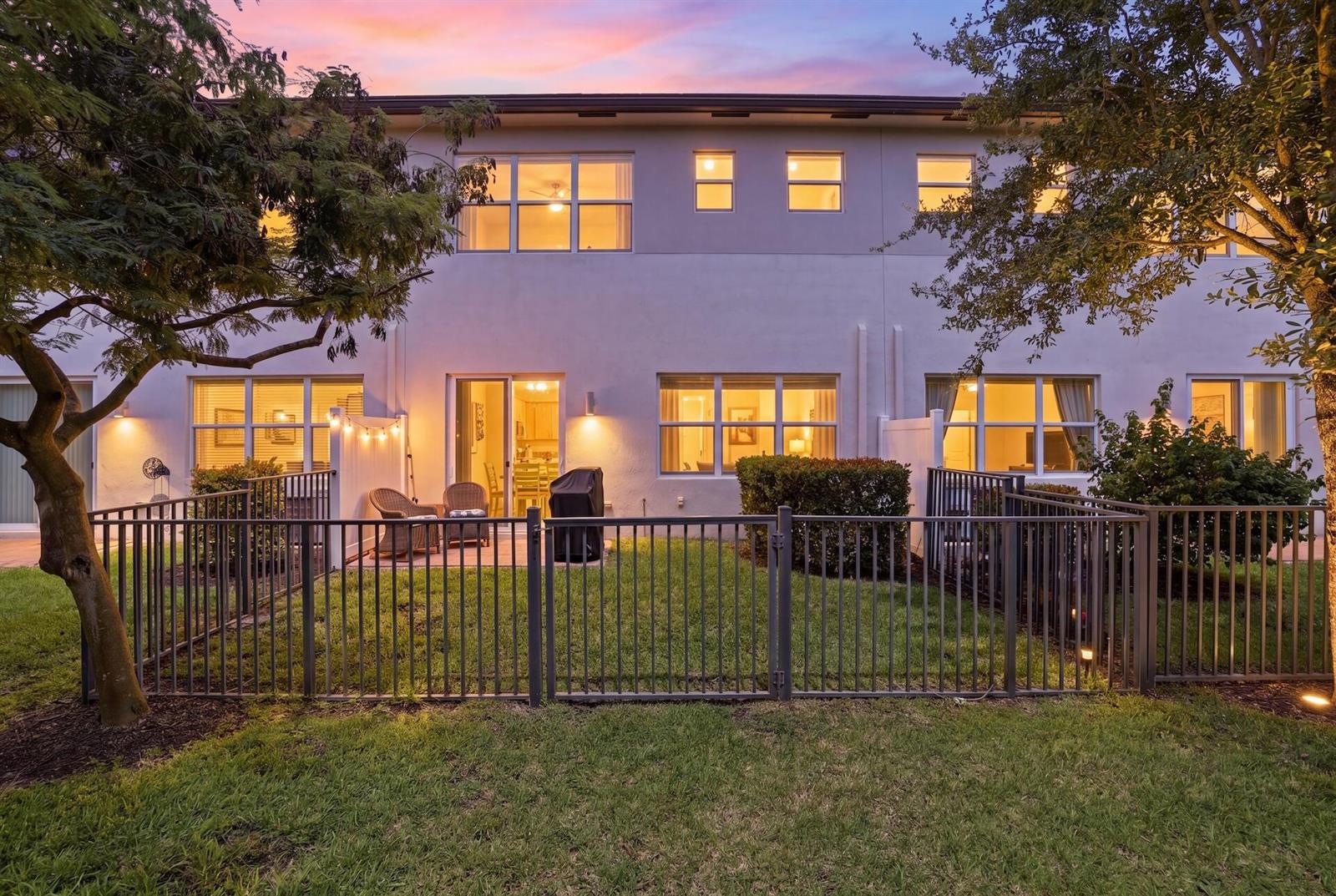 The exterior of a two-story townhouse features a fenced backyard with a patio and lawn — 4779 Navali Drive, Lake Worth FL 33467, LAKE WORTH, FL
