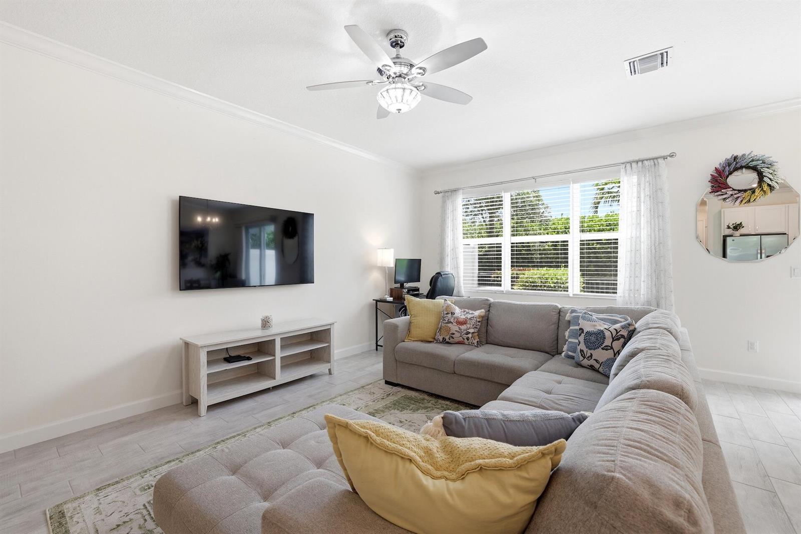 A living room features a grey sectional sofa, a wall-mounted television, and a ceiling fan — 4779 Navali Drive, Lake Worth FL 33467, LAKE WORTH, FL