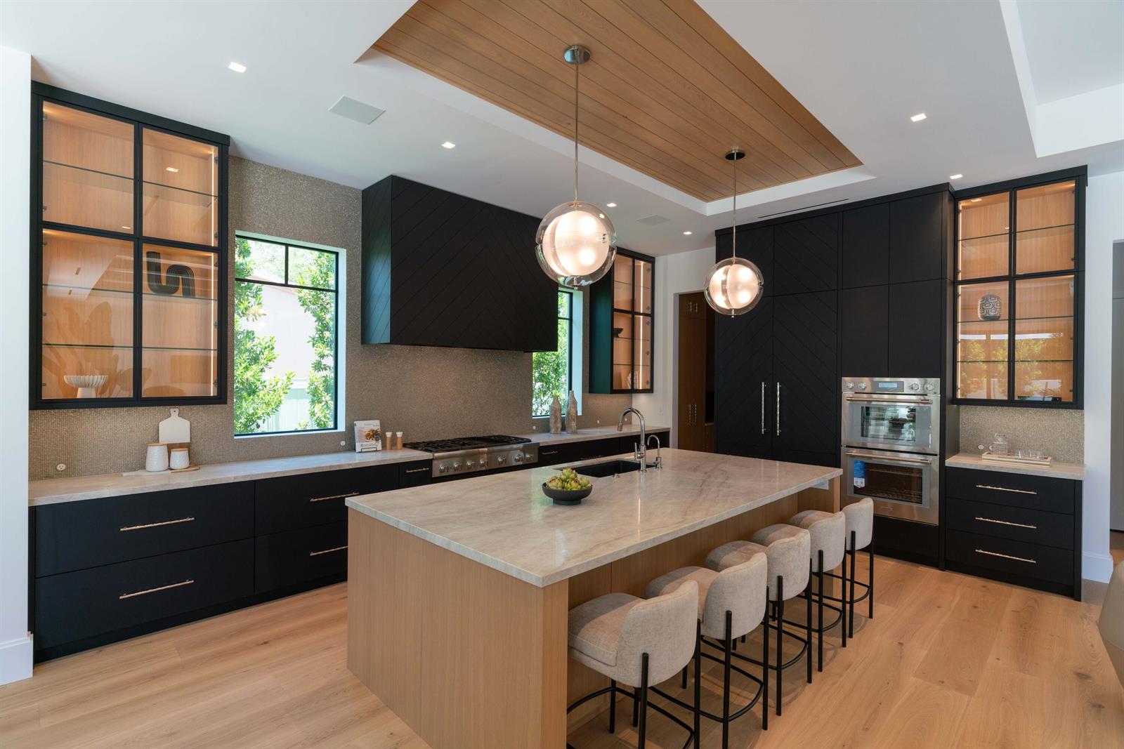 A modern kitchen features black cabinetry, a wood-paneled ceiling, and a large marble-topped island — 720 NW 3rd Avenue, Delray Beach FL 33444, DELRAY BEACH, FL
