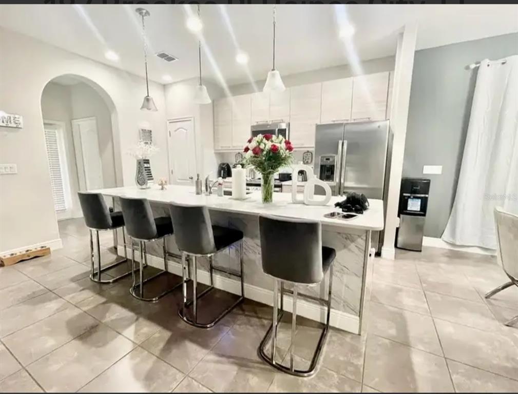 A kitchen features a large marble-topped island with four gray bar stools and stainless appliances — 187 BROOKES PLACE, HAINES CITY, FL
