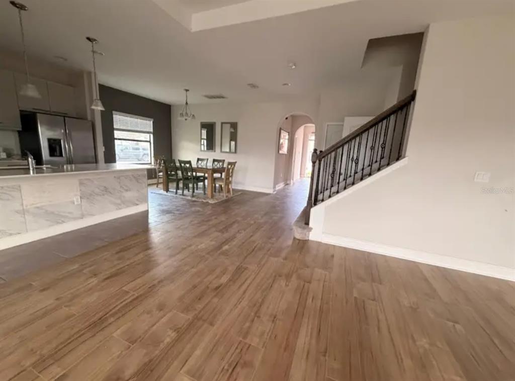 An open-concept kitchen and dining area features wood-look tile flooring and a staircase — 187 BROOKES PLACE, HAINES CITY, FL
