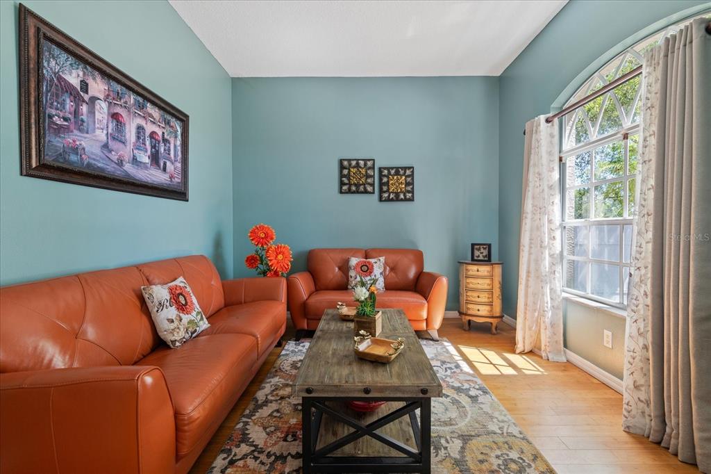 A living room features two orange leather sofas, a wooden coffee table, and blue walls — 5001 44TH AVENUE N, ST PETERSBURG, FL