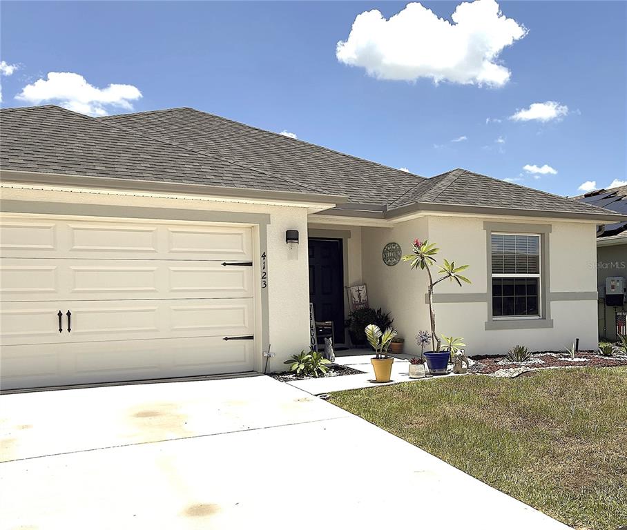 A single-story house with a beige stucco exterior, a two-car garage, and a front entrance — 4123 RUBY RUN, HAINES CITY, FL
