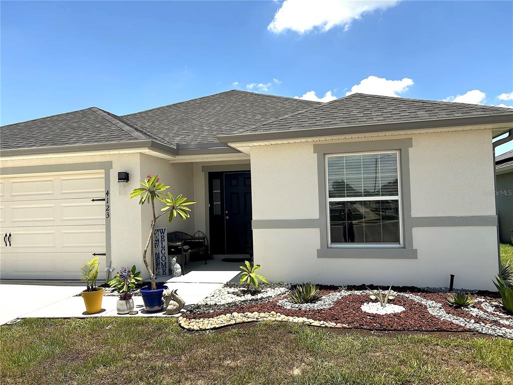 A single-story house with a white stucco exterior, gray trim, and a landscaped front yard — 4123 RUBY RUN, HAINES CITY, FL