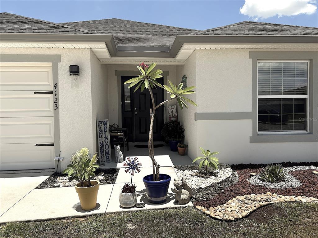The exterior of a house features a front entrance, a garage, and potted plants — 4123 RUBY RUN, HAINES CITY, FL