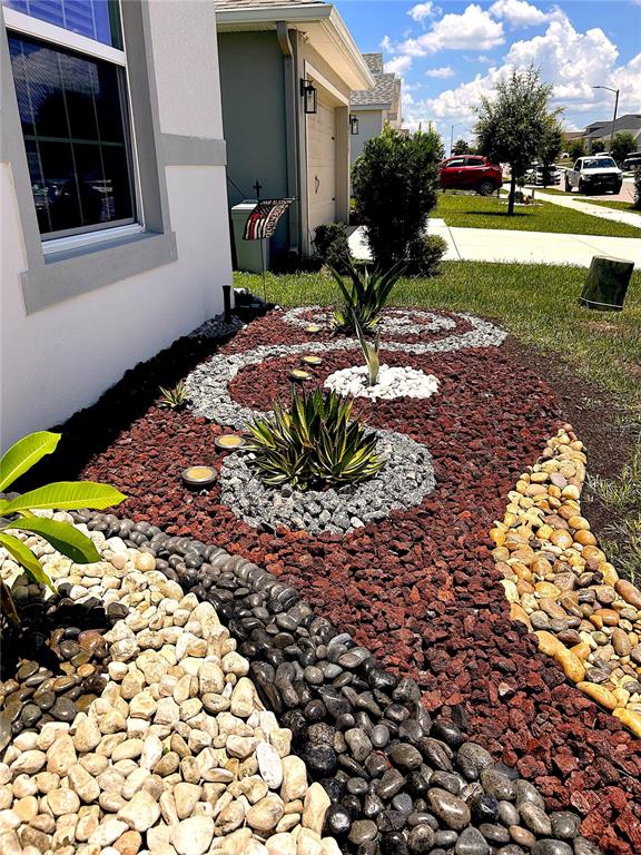 A landscaped garden bed features red lava rock, decorative river stones, and several agave plants — 4123 RUBY RUN, HAINES CITY, FL