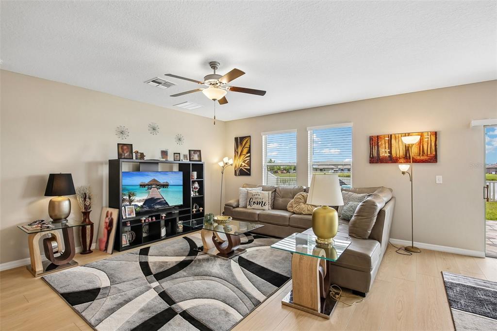 A living room features a sectional sofa, a television console, and a patterned area rug — 15608 MILLER CREEK DRIVE, SUN CITY CENTER, FL