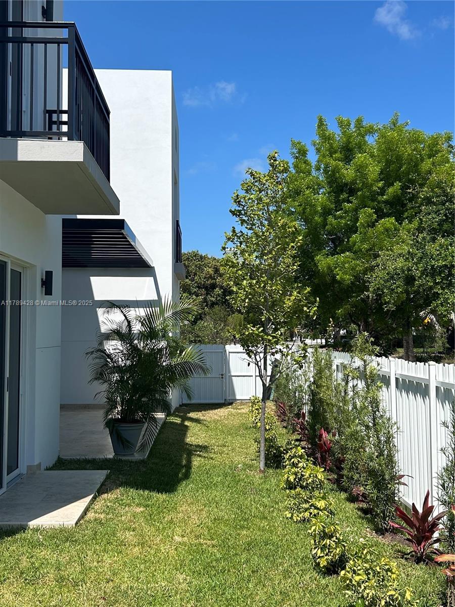 A white modern building exterior features a small grassy yard with a white fence — 900 SW 24th Rd, Miami FL 33129, MIAMI, FL