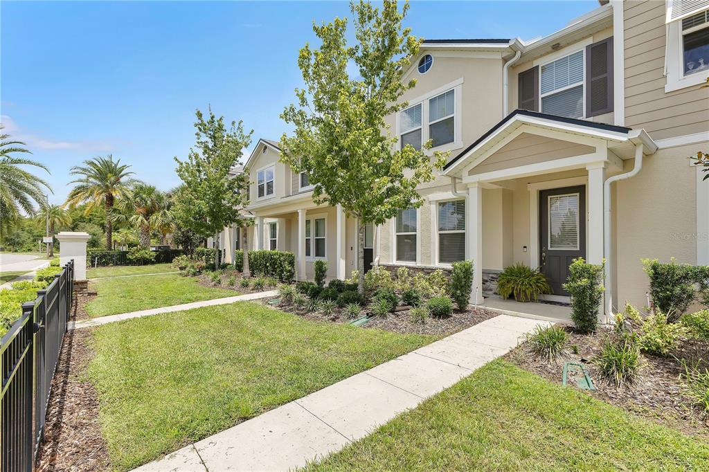 A two-story townhouse exterior with a tan facade, a front walkway, and a small lawn — 9421 RANDAL PARK BOULEVARD, ORLANDO, FL