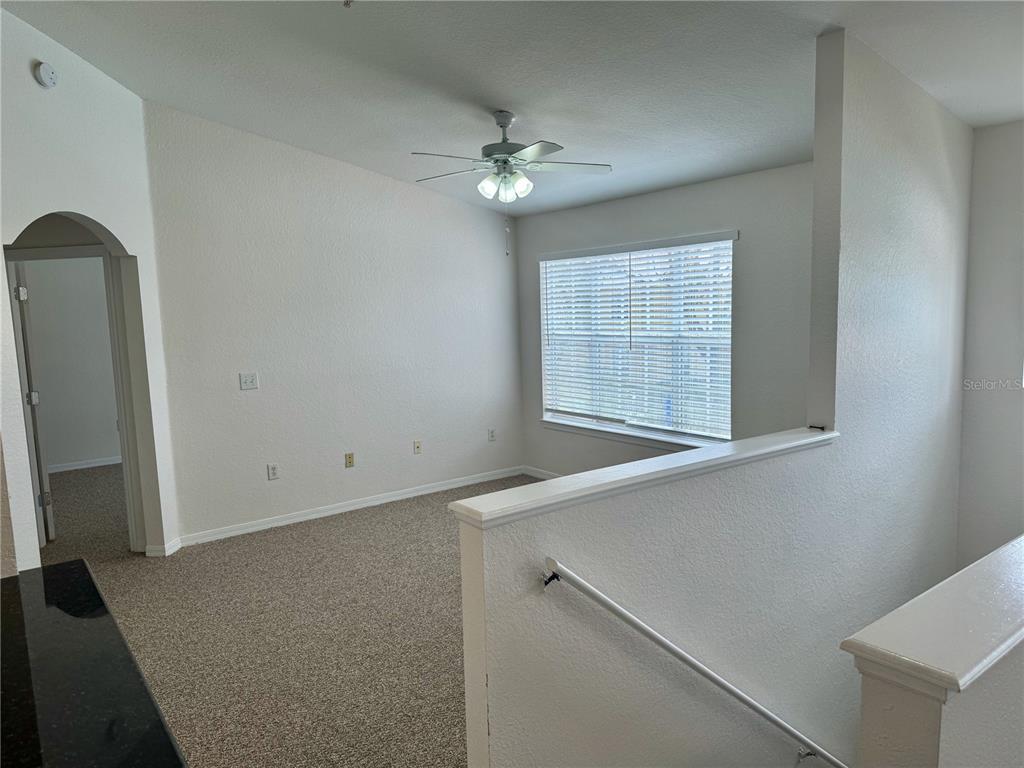 An upstairs carpeted loft area features a ceiling fan, a window with blinds, and stairs — 832 GRAND REGENCY POINT UNIT 204, ALTAMONTE SPRINGS, FL