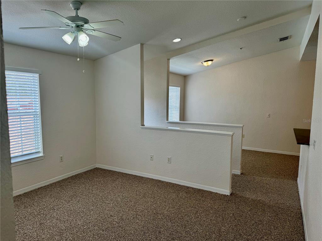 An empty room with beige carpet, a ceiling fan, and a partial wall divider — 832 GRAND REGENCY POINT UNIT 204, ALTAMONTE SPRINGS, FL
