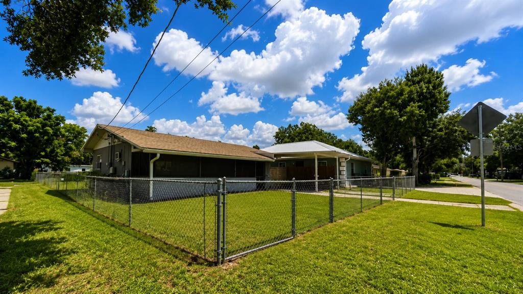A fenced-in backyard with a house featuring a screened porch and a metal carport — 3319 AVENUE U NW, WINTER HAVEN, FL