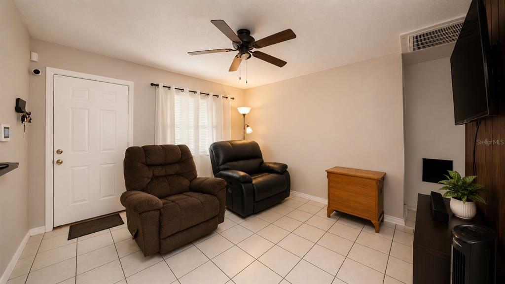 A living room features two recliners, a wooden cabinet, a ceiling fan, and tiled flooring — 3319 AVENUE U NW, WINTER HAVEN, FL