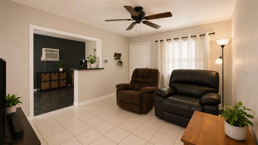 A living room features tile flooring, two armchairs, a ceiling fan, and a pass-through window — 3319 AVENUE U NW, WINTER HAVEN, FL