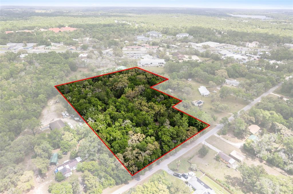 An aerial view shows a wooded, L-shaped plot of land outlined in red — 2322 W MAIN STREET, INVERNESS, FL