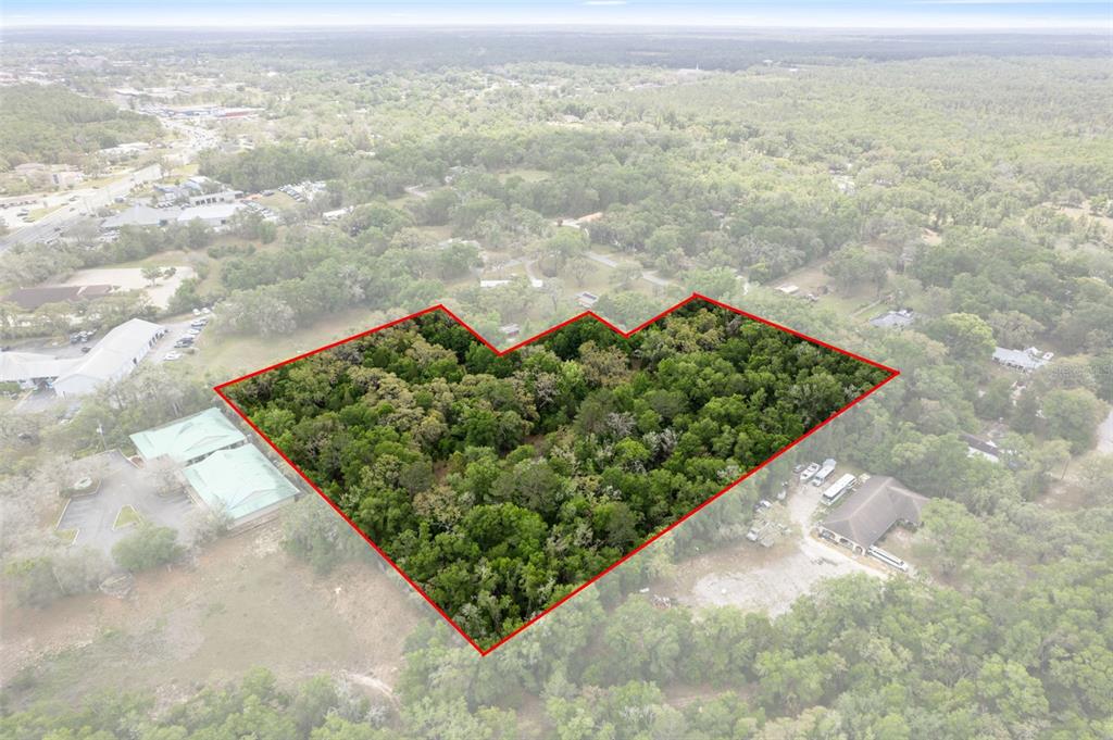 An aerial view shows a wooded plot of land outlined in red — 2322 W MAIN STREET, INVERNESS, FL