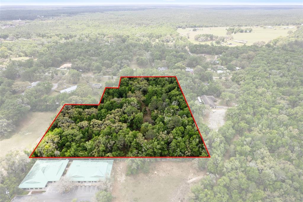 An aerial view shows a wooded plot of land outlined in red near a building — 2322 W MAIN STREET, INVERNESS, FL