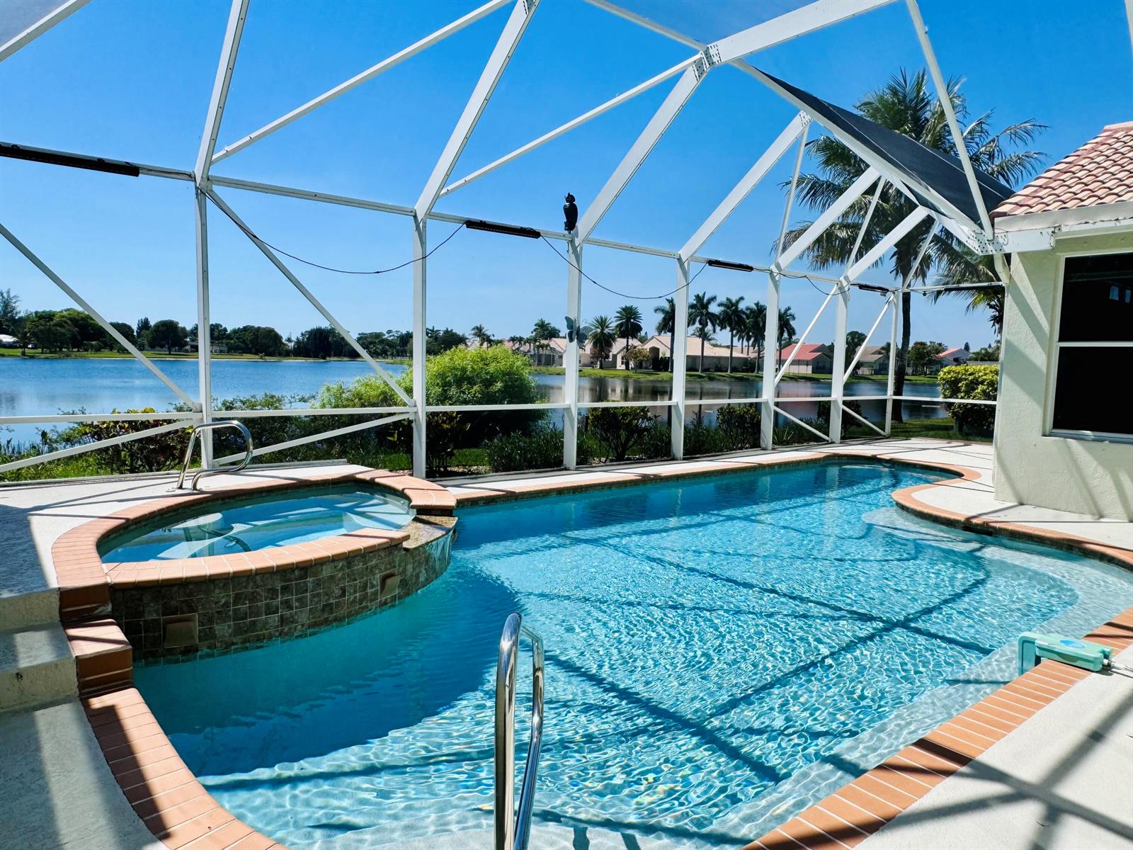 A swimming pool and spa enclosed by a screened lanai overlooking a lake — 9360 Cove Point Circle, Boynton Beach FL 33472, BOYNTON BEACH, FL