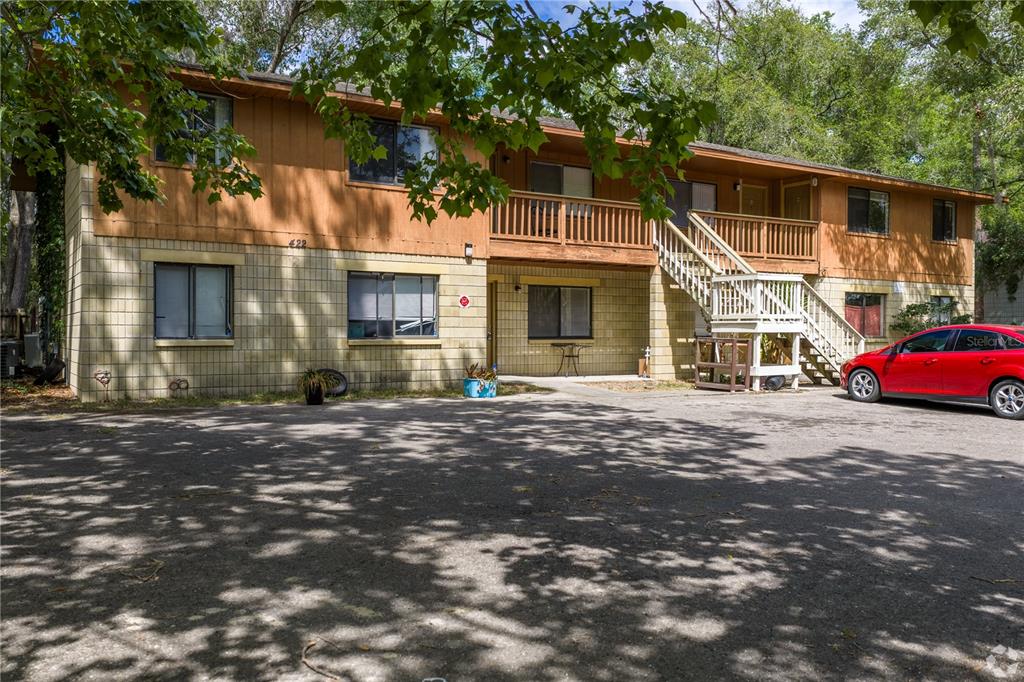 A two-story apartment building with a wooden balcony, exterior staircase, and a paved parking lot — 422 SW 69TH STREET, GAINESVILLE, FL