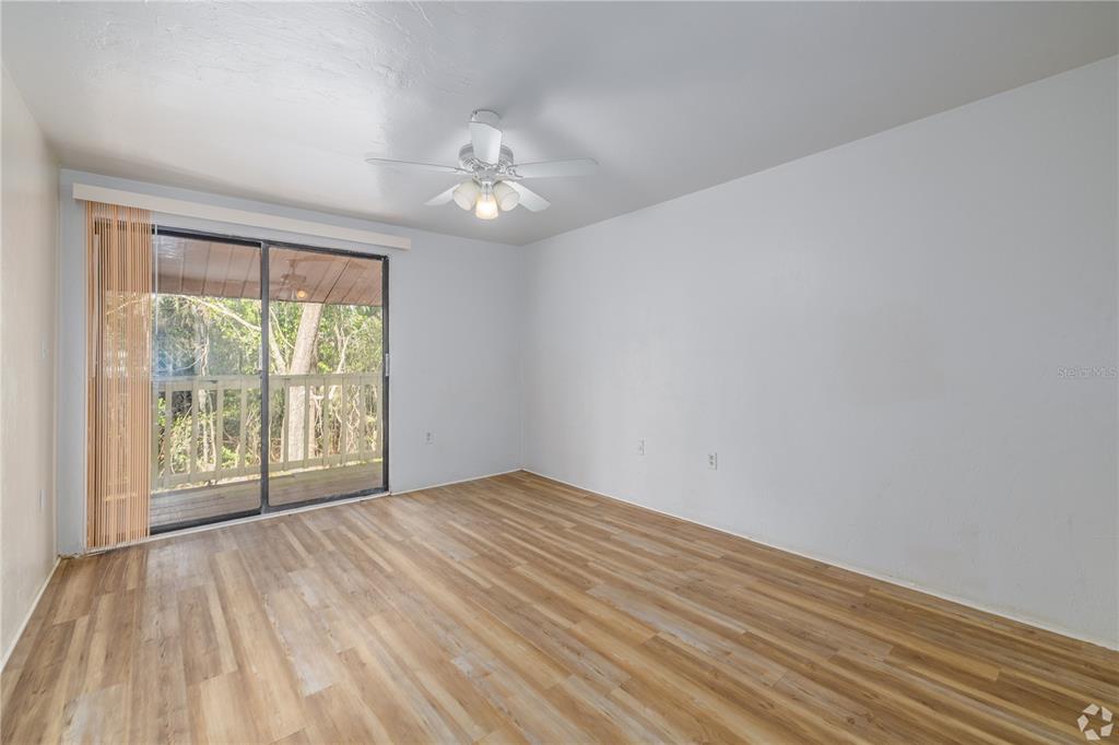An empty room with light wood-look flooring, a ceiling fan, and a sliding glass door — 422 SW 69TH STREET, GAINESVILLE, FL
