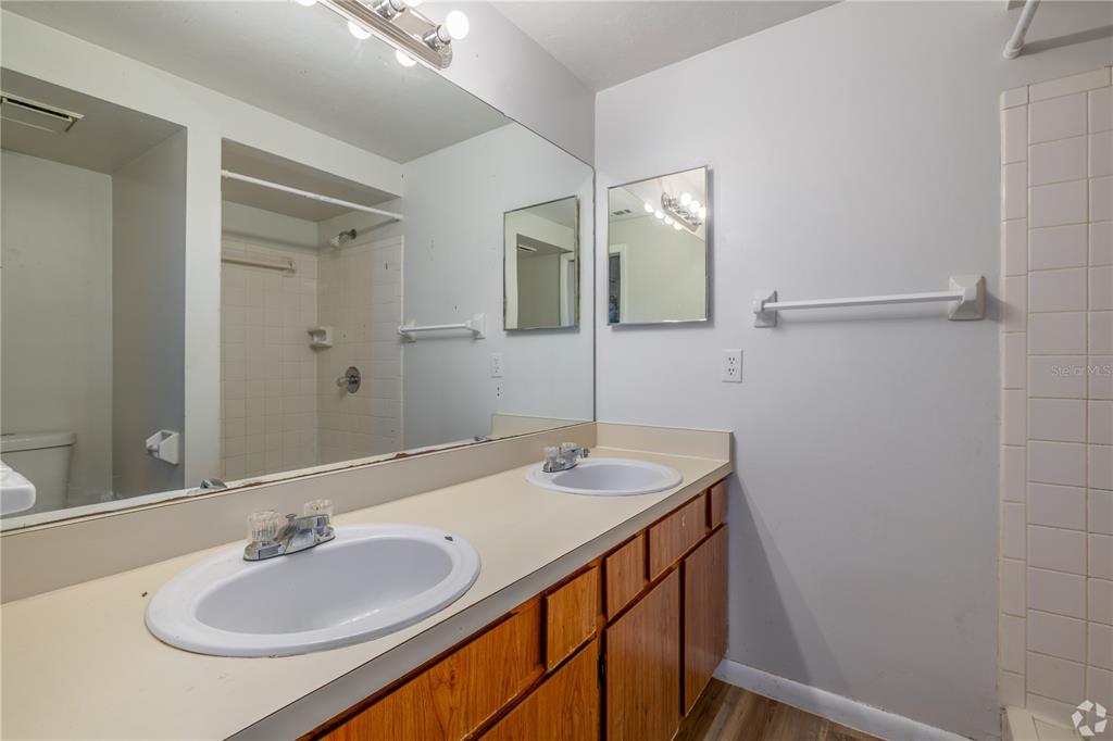 A bathroom features a double vanity with wood cabinets, a large mirror, and a shower — 422 SW 69TH STREET, GAINESVILLE, FL