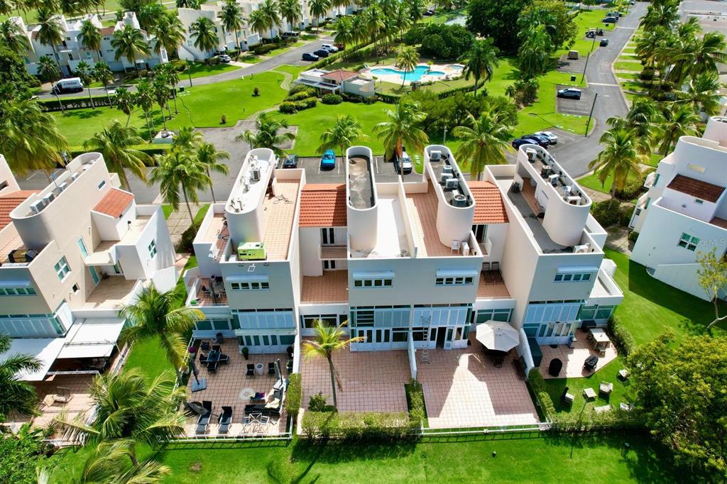 An aerial view of a multi-story residential building with rooftop structures and private ground-level patios — #124 VILLAS DE GOLF OESTE, DORADO, PR