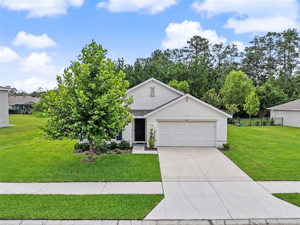A single-story house with a white exterior, a two-car garage, and a large front tree — 5038 CADIZ COURT, BROOKSVILLE, FL