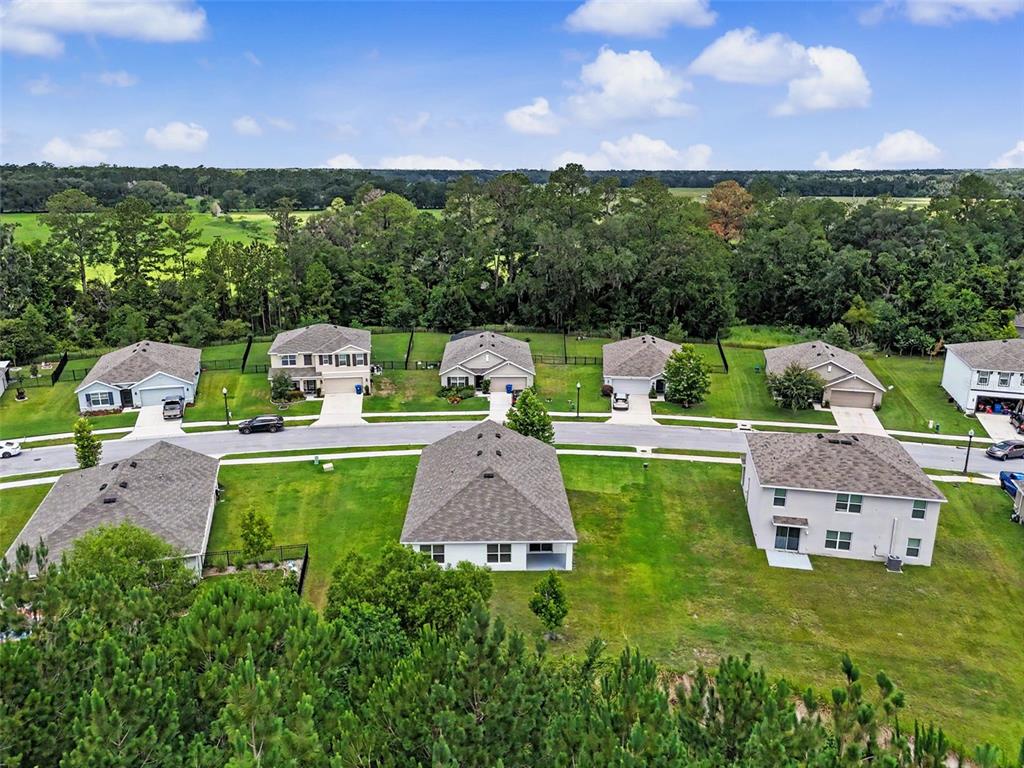 An aerial view shows several suburban houses with gray roofs and green lawns — 5038 CADIZ COURT, BROOKSVILLE, FL